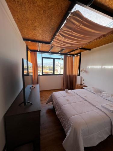 a bedroom with a large bed and a large window at Hotel SOGU TOWER in Ayacucho