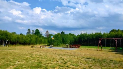 a park with benches and picnic tables in a field at Brzozowa Polana in Perlino