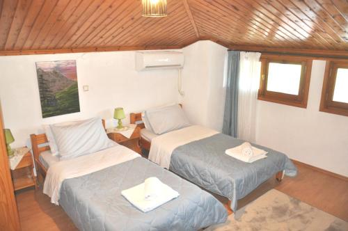 Habitación pequeña con 2 camas y silla en Cozy Loft with Fireplace & View, en Metsovo