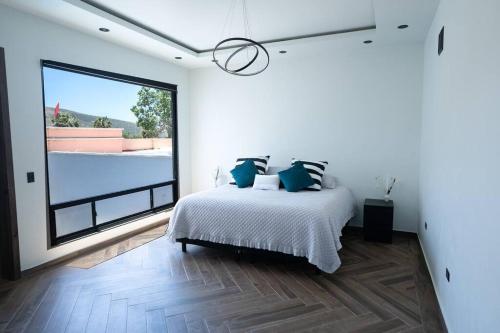 een witte slaapkamer met een bed en een groot raam bij Casa Alvana in Ensenada