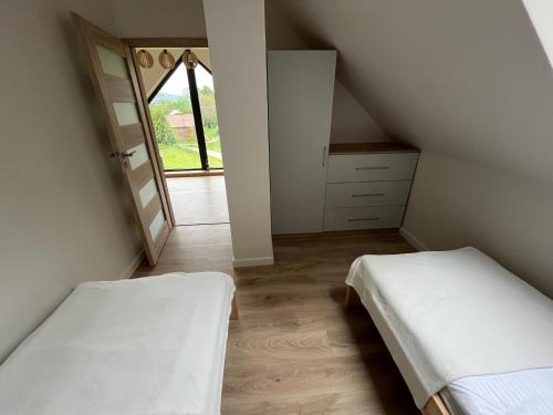 a attic bedroom with two beds and a window at Szopówka Pod Grodziskiem in Dukla