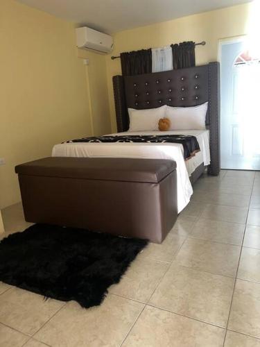 1 dormitorio con 1 cama grande y cabecero marrón en Emperor’s place Garvey mead, en Portmore