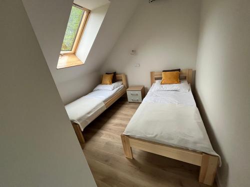 twee bedden in een kleine kamer met een raam bij Szopówka Pod Grodziskiem in Dukla
