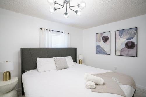 a bedroom with a large white bed and a chandelier at Modern 3-Bedroom in the Heart of Wynwood Art District in Miami