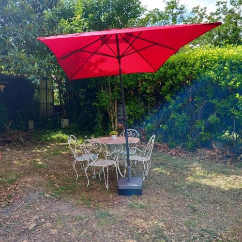 a table and chairs under a red umbrella at Love Room avec spa in Nérac