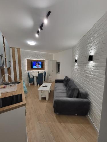 - un salon avec un canapé noir et un mur en briques dans l'établissement HARMONY Suites (Savska ulica), à Sajmište