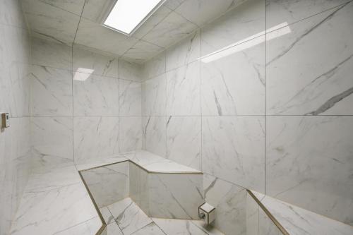 een badkamer met witte marmeren muren en een dakraam bij The Resorts Of Pelican Beach 1613 Destin (Condo) in Destin