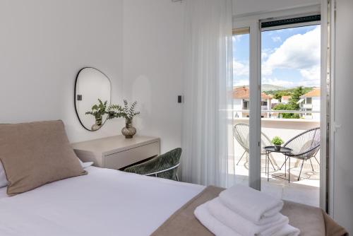een witte slaapkamer met een bed en een balkon bij Apartments Ocrux in Trogir