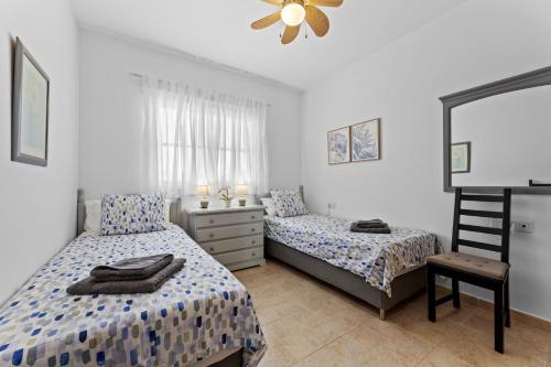 a bedroom with two beds and a chair and a dresser at Casahost Fuerteventura Golf in La Guirra