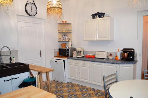 une cuisine avec des placards blancs et une horloge murale dans l'établissement domaine de l hyères, à Grandcourt