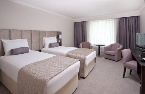 a hotel room with two beds and a television at Sudbury House in Faringdon