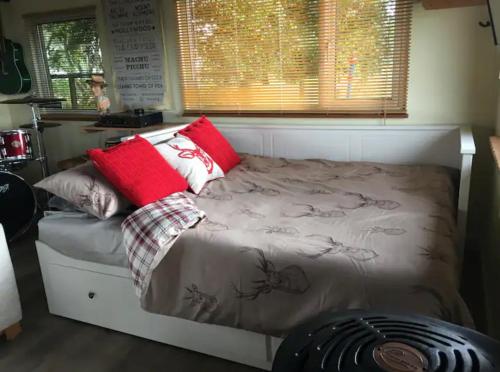 Bett mit roten Kissen auf einem Zimmer in der Unterkunft Angies Den - quirky cabin with hot tub & views in Llanasa