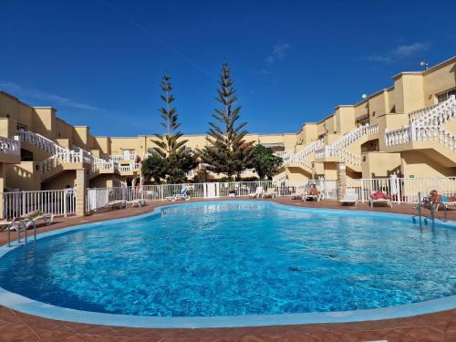 a large swimming pool in front of some apartment buildings at Apartament CALETA in Caleta De Fuste