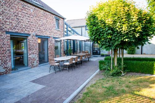 a patio with a table and chairs and a tree at Boutique Hotel Het Zoete Zijn in Borgloon