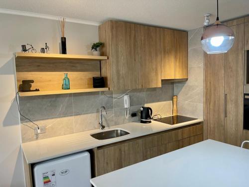a kitchen with wooden cabinets and a sink at Departamento Nuevo!!! Sector Residencial Ciudad Iquique in Iquique