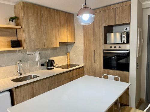 a kitchen with wooden cabinets and a white counter top at Departamento Nuevo!!! Sector Residencial Ciudad Iquique in Iquique