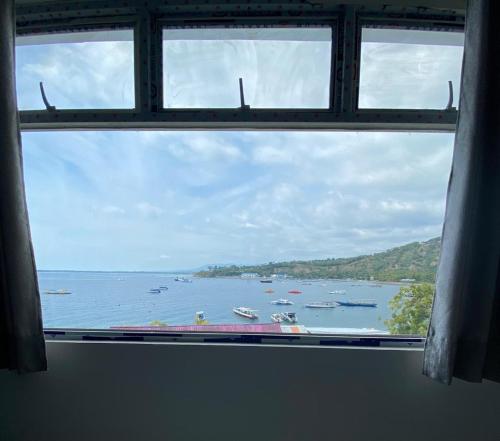 uma janela com vista para uma grande massa de água com barcos em Anugrah Hotel em Teluknarat