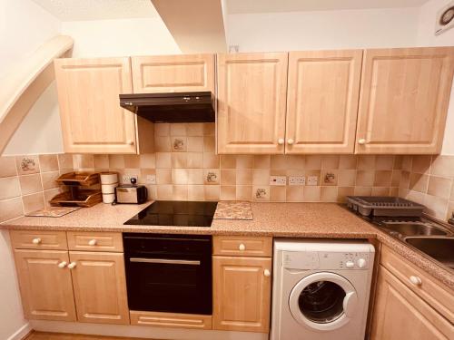 a kitchen with wooden cabinets and a dishwasher at Leicester city centre flat in Leicester