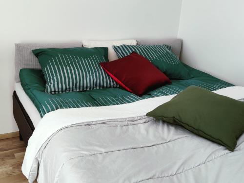 a bed with green and red pillows on it at Ydinkeskustassa, uusi yksiö+ autohallipaikka in Tampere