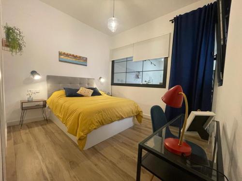 1 dormitorio con cama amarilla y mesa de cristal en APARTAMENTOS SOL Y LUNA, en La Línea de la Concepción