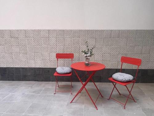 two red chairs and a table with a vase of flowers at APARTAMENTOS SOL Y LUNA in La Línea de la Concepción