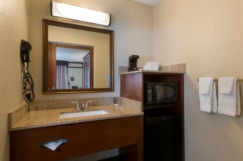 a bathroom with a sink and a mirror and a microwave at Rosen Inn Closest to Universal in Orlando