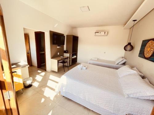 a bedroom with a bed and a desk and a television at Pousada Quintal da Lua in Capitólio