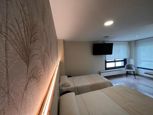 a hotel room with two beds and a television at Hostal LA POETISA - Auto Check-in in Culleredo