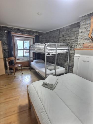 a bedroom with two bunk beds and a brick wall at Auberge de la Paix in Quebec City