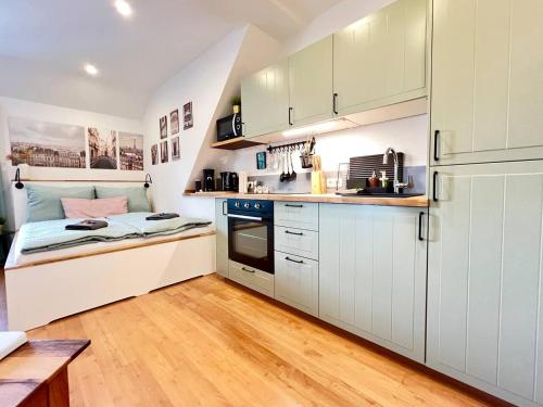 uma pequena cozinha com armários brancos e uma cama em Stilvolles Mikroapartment in Kehl Goldscheuer - 1A Guesthouse em Kehl am Rhein