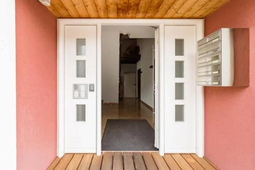 une porte menant à une chambre avec un mur rose dans l'établissement Stilvolles Mikroapartment in Kehl Goldscheuer - 1A Guesthouse, à Kehl