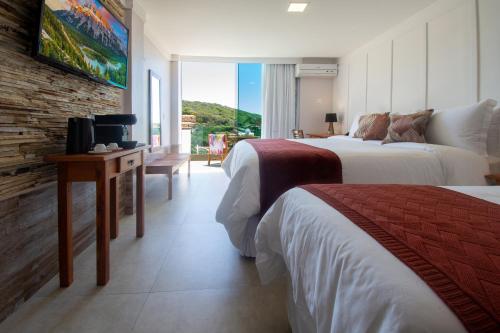 a hotel room with two beds and a window at Hotel Pousada Experience João Fernandes in Búzios