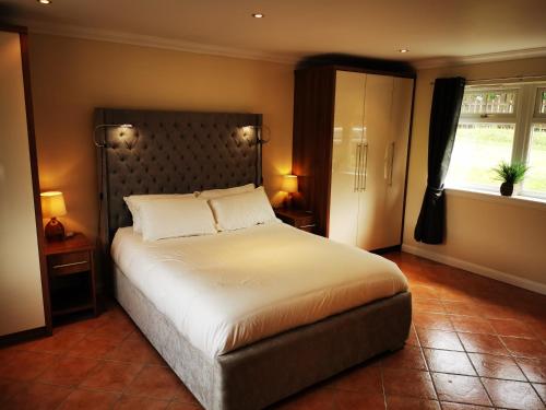 um quarto com uma cama grande e 2 janelas em Private peacefull pet friendly converted country cottage 