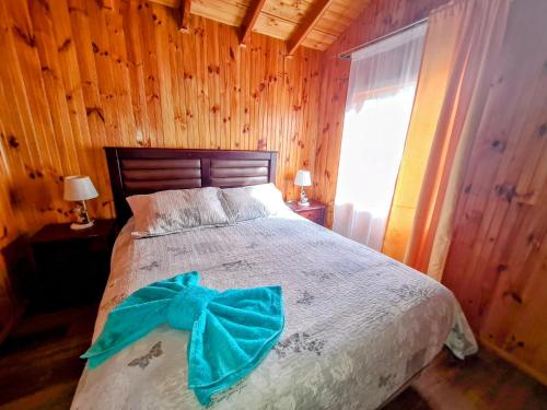 a bedroom with a bed with a blue bow on it at Cabañas Kompatzki in Ancud