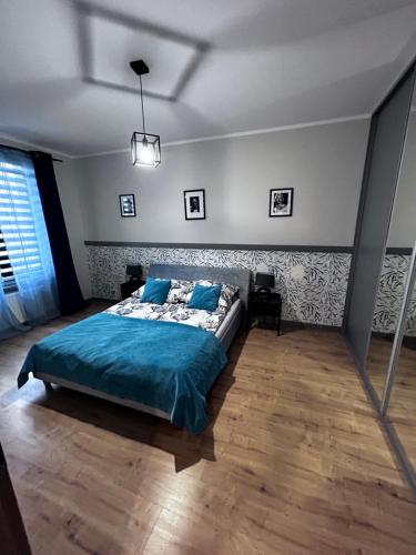 ein Schlafzimmer mit einem Bett mit einer blauen Bettdecke in der Unterkunft Apartament Walczaka 47 MIEJSCE PARKINGOWE in Gorzów Wielkopolski