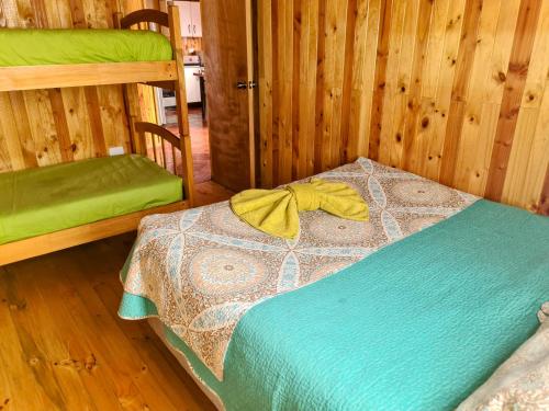 a bedroom with a bed with a yellow towel on it at Cabañas Kompatzki in Ancud