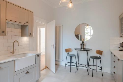 a kitchen with a sink and two bar stools at Lux and Spacious 4 bedroom apt Camden in London