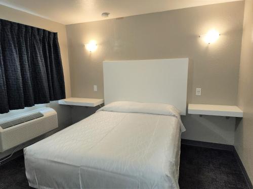 1 dormitorio pequeño con 1 cama blanca y 2 luces en Morada Inn, en Anaheim