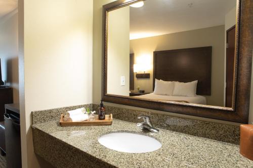 a bathroom with a sink and a large mirror at Oxford Suites Pendleton in Pendleton