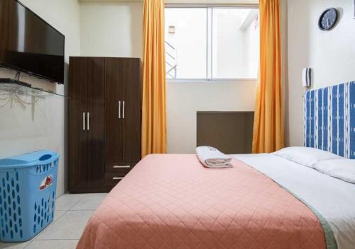a bedroom with a bed with a television and orange curtains at 203 RV Apartments Iquitos-Apartamento con dos habitaciones in Iquitos