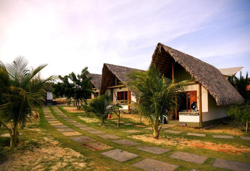 a house with a thatched roof and palm trees at Chalé Sienna Ar condicionado Pousada 35knots Brasil in Luis Correia