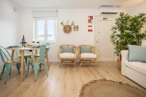 a living room with a table and chairs and a couch at CASA BRISA, MAR E SOL SESIMBRA in Sesimbra