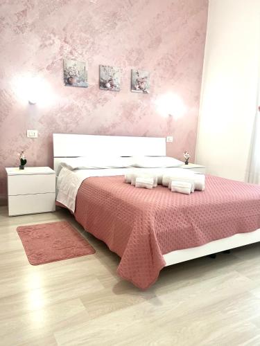 a bedroom with a large bed with a pink wall at Minù house in Scalea