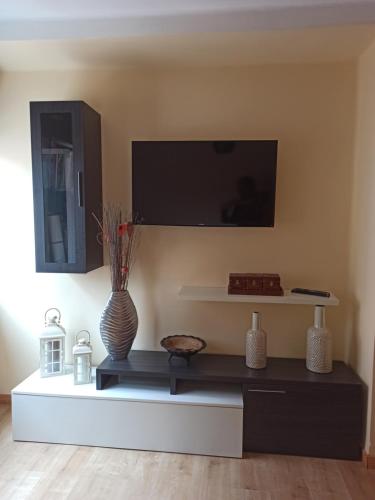 - un salon avec une télévision et un vase sur une table dans l'établissement Apartamento El Pórtico de Muros, à Muros de Nalón