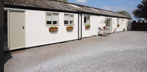 a row of white buildings with potted plants on them at Rivington Barn in Kerne Bridge