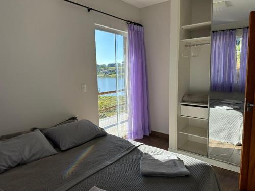 a bedroom with a bed and a large window at Casa no Condomínio Naútico Porto da Pedra em Ijaci in Macaia