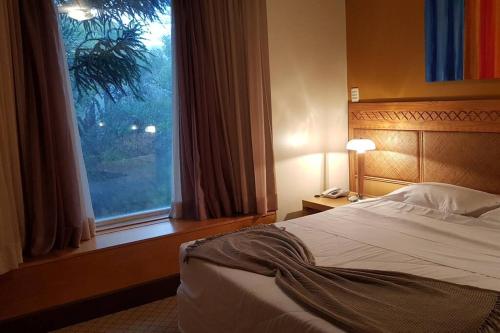 Cama en habitación de hotel con ventana en Luxuoso Flat Mountain Village, en Canela