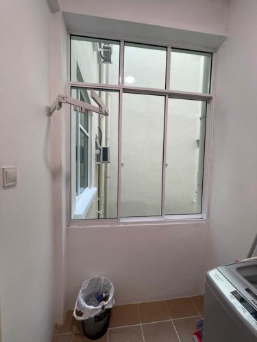 a bathroom with a window and a trash can at Inns Homestay in Sandakan