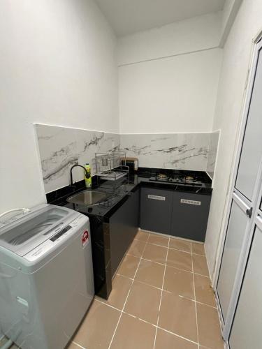 a small kitchen with a sink and a dishwasher at Inns Homestay in Sandakan