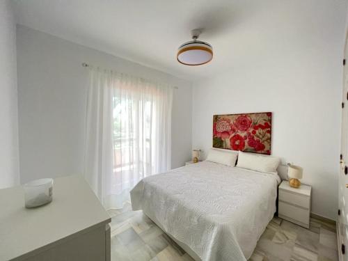 a white bedroom with a bed and a painting on the wall at costa ballena elite in Costa Ballena